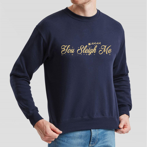 Navy Blue Jumper with slogan You Sleigh Me in gold effect print across the chest surrounded by tiny snowflakes and the silhouette of Santa’s sleigh pulled by a team of reindeer.